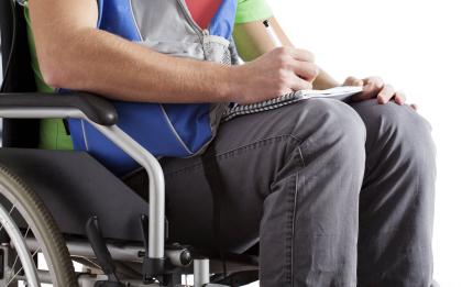 person in wheel chair writing on notepad