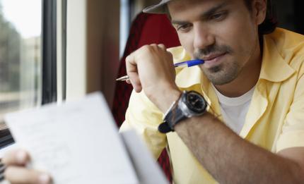 Man sucking on his pen reading 