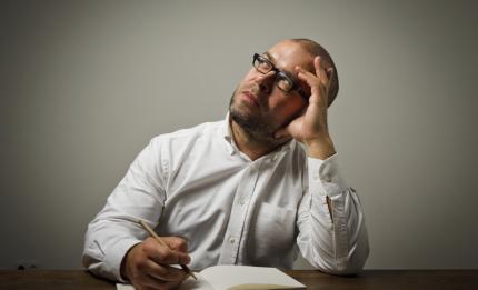 Man with hand on his head thinking with pen in the other hand