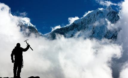 mountain climber with pick axe looking at snowy mountain scene