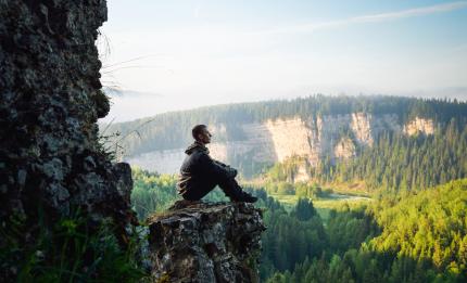 Man thinking on top of a rock