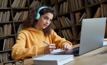 Women writing at desk with computer