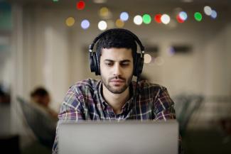 A man working on his laptop with headphones on