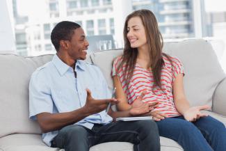 a man and a woman talking on a sofa