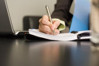 a hand holding a pen and writing in a note book