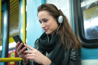 woman with headphones on looking at her phone