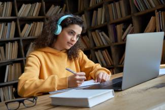 Women writing at desk with computer