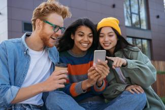 three friends smiling at a mobile phone screen