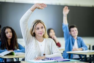 A student in a classroom raising her hand