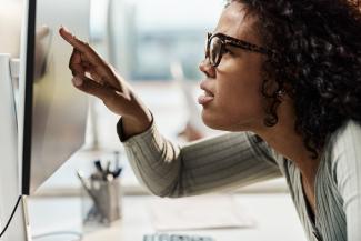 A woman pointing at a word on a computer screen and looking confused