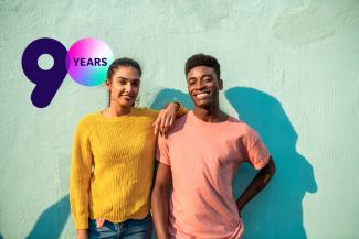 Two young people smiling with a logo that says "90 years" in the background